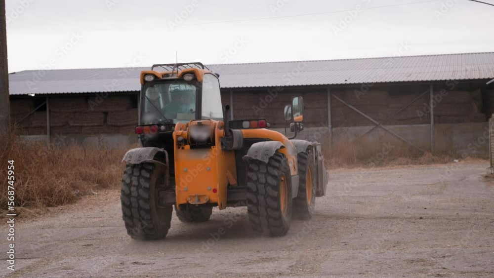 farm machinery, modern tractor driving on road on farm for a haystack for feeding cattle on cloudy day farm machinery, modern tractor driving on road on farm for a haystack for feeding cattle on cloudy day