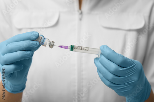 Doctor filling syringe with hepatitis vaccine from glass vial, closeup