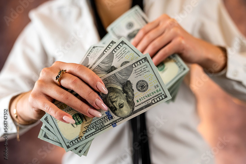 Cropped photo of a woman holding US dollar money in her hands on the background of her body.