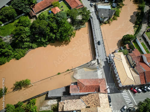 Rio cheio visto de cima casas alagadas com fundo para paisagem.