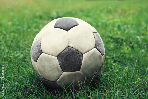 Dirty soccer ball on fresh green grass outdoors  closeup