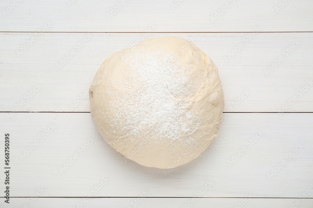 Fresh yeast dough with flour on white wooden table, top view