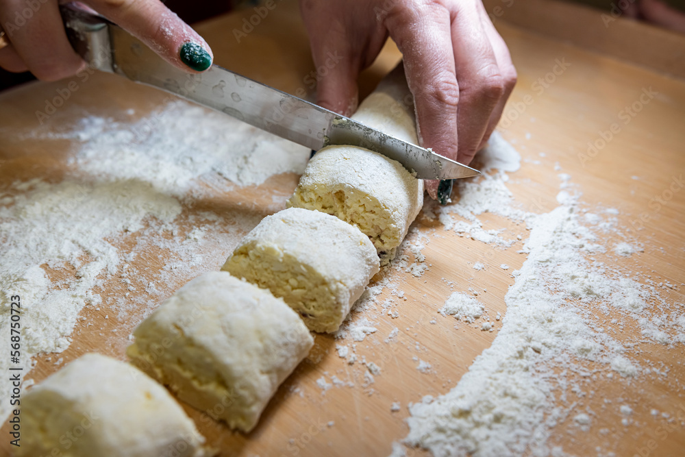professional baker with knife cuts the raw sausage dough into even small pieces