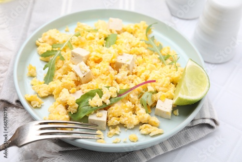 Delicious scrambled eggs with tofu and lime served on white table, closeup
