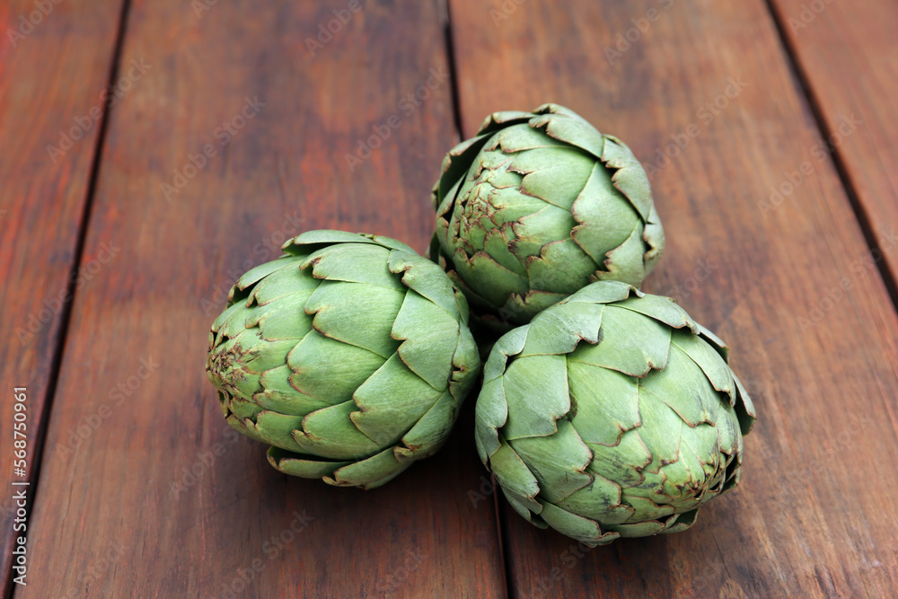 Obraz premium Fresh raw artichokes on wooden table, closeup