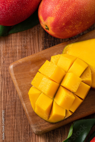 Fresh mango fruit with leaves over dark wooden table background.