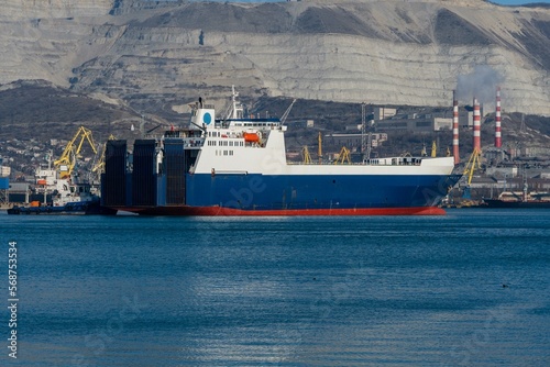 Novorossiysk Commercial Sea Port. Cargo Ship. Ferry Ulusoy 5 Sea Line  accompanied by pilot tug, moves along Tsemess Bay to open sea. Blurred background. Novorossiysk, Russia - December 20, 2022 photo