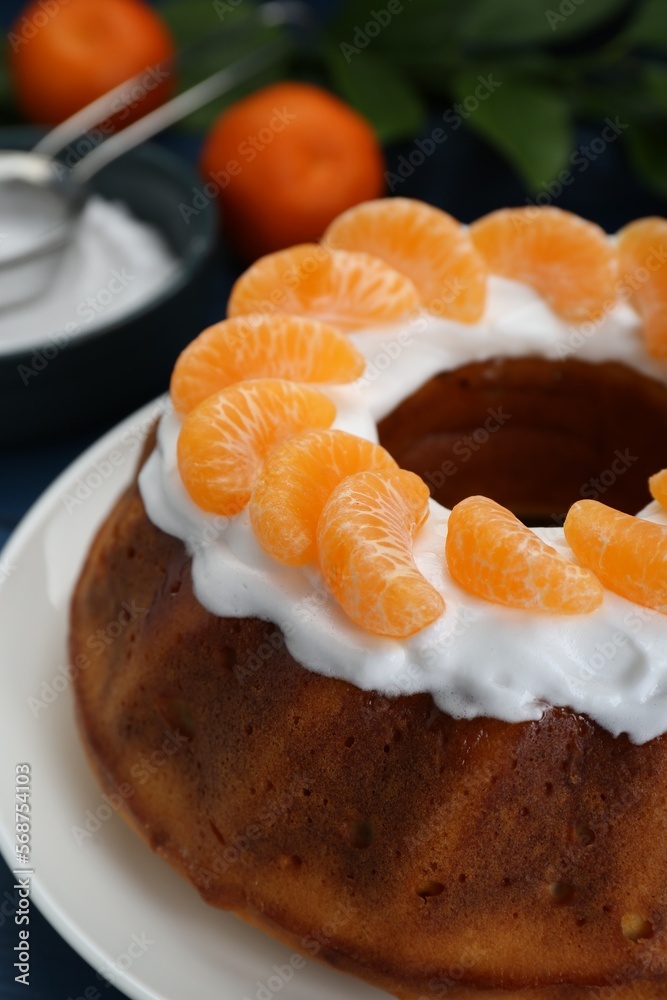 Homemade yogurt cake with tangerines and cream on blue wooden table, closeup Homemade yogurt cake with tangerines and cream on blue wooden table, closeup