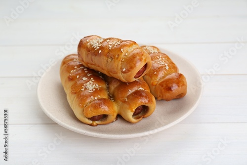 Delicious sausage rolls on white wooden table