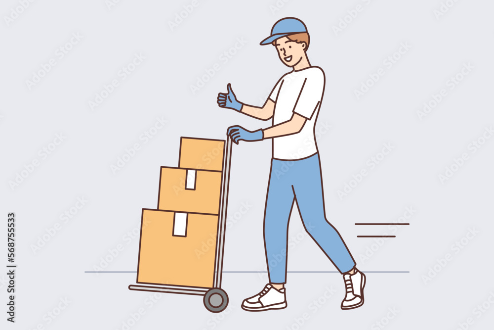 Man at warehouse worker carries cargo cart with cardboard boxes and shows thumbs up Man at warehouse worker carries cargo cart with cardboard boxes and shows thumbs up