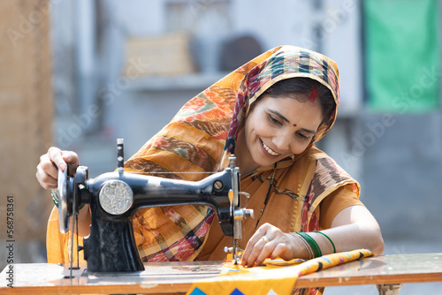 Indian rural woman using sewing machine at home