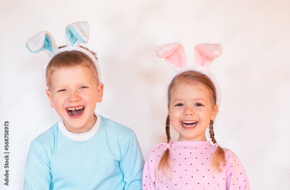 two smiling happy children with Easter bunny ears looking at camera on white background, copy space
two smiling happy children with Easter bunny ears looking at camera on white background, copy space