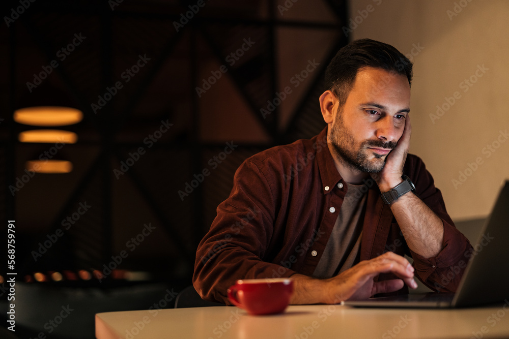 Concentrated businessman using a laptop, working over it, staying overtime at the office. Concentrated businessman using a laptop, working over it, staying overtime at the office.