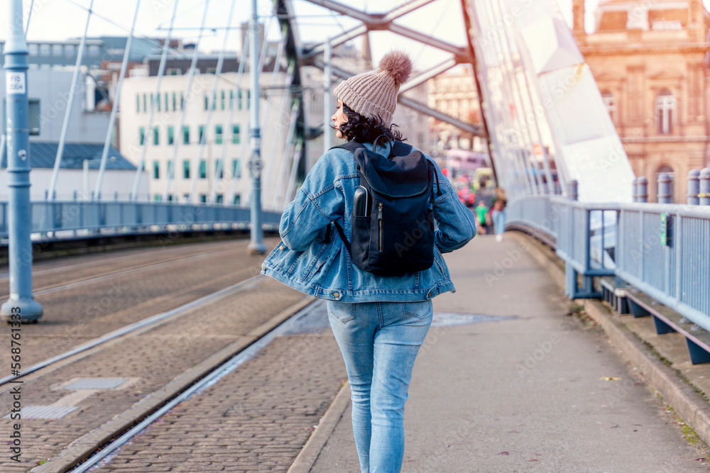 a young woman in a denim jacket is talking on the phone and waiting for a tram, bus at the stop Lifestyle photo