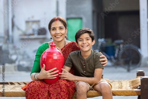 Photography Rural mother with son saving money in piggy bank for future education