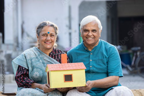 Senior happy couple holding dream house model.