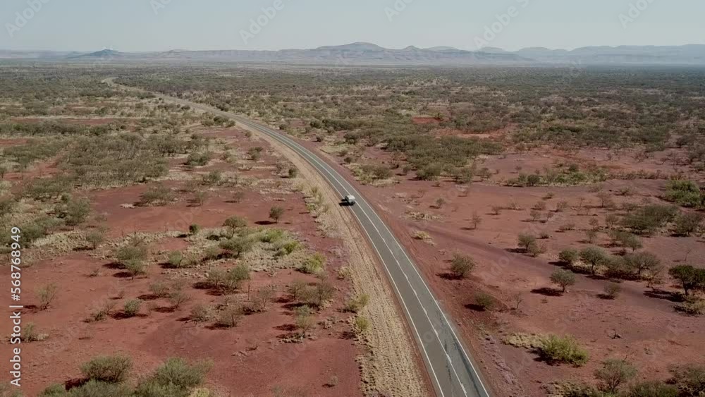 Rising aerial view of a lone car driving through Austalia's Karijini National Park in the heat of the day. Rising aerial view of a lone car driving through Austalia's Karijini National Park in the heat of the day.