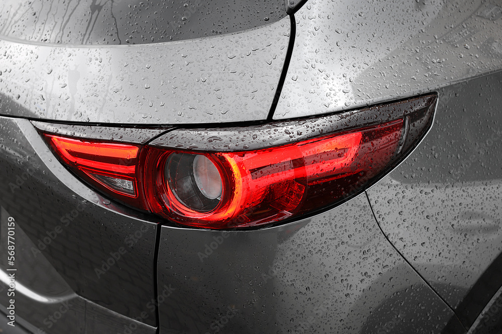 Obraz premium Car with switched on tail light in drops of water, closeup