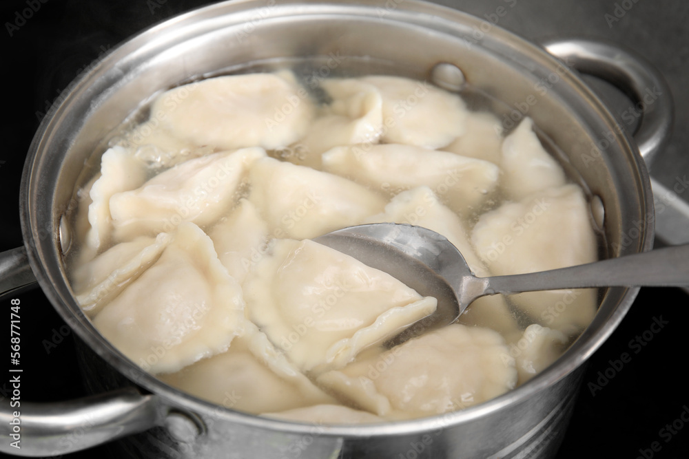 Cooking dumplings (varenyky) with tasty filling in pot indoors, closeup Cooking dumplings (varenyky) with tasty filling in pot indoors, closeup