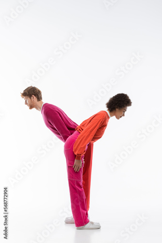 side view of interracial couple in magenta color clothes showing y letter on white background.
