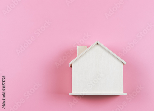 flat lay of wooden model house on pink background.