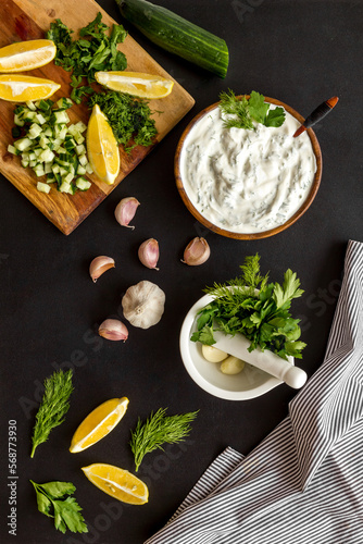 Bowl of dip sauce sour cream with ingredients - herbs and cucumber