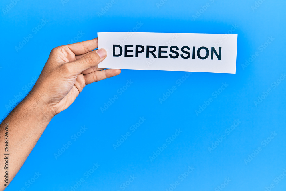 Hand of caucasian man holding paper with depression word over isolated blue background Hand of caucasian man holding paper with depression word over isolated blue background
