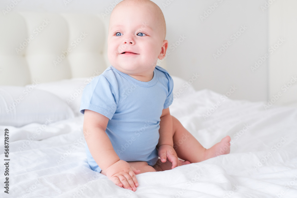 portrait of smiling baby boy with big blue eyes in bodysuit on white bedding. Healthy newborn child portrait of smiling baby boy with big blue eyes in bodysuit on white bedding. Healthy newborn child