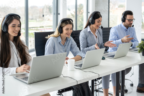 Group of friendly customer care support operators working in call center.