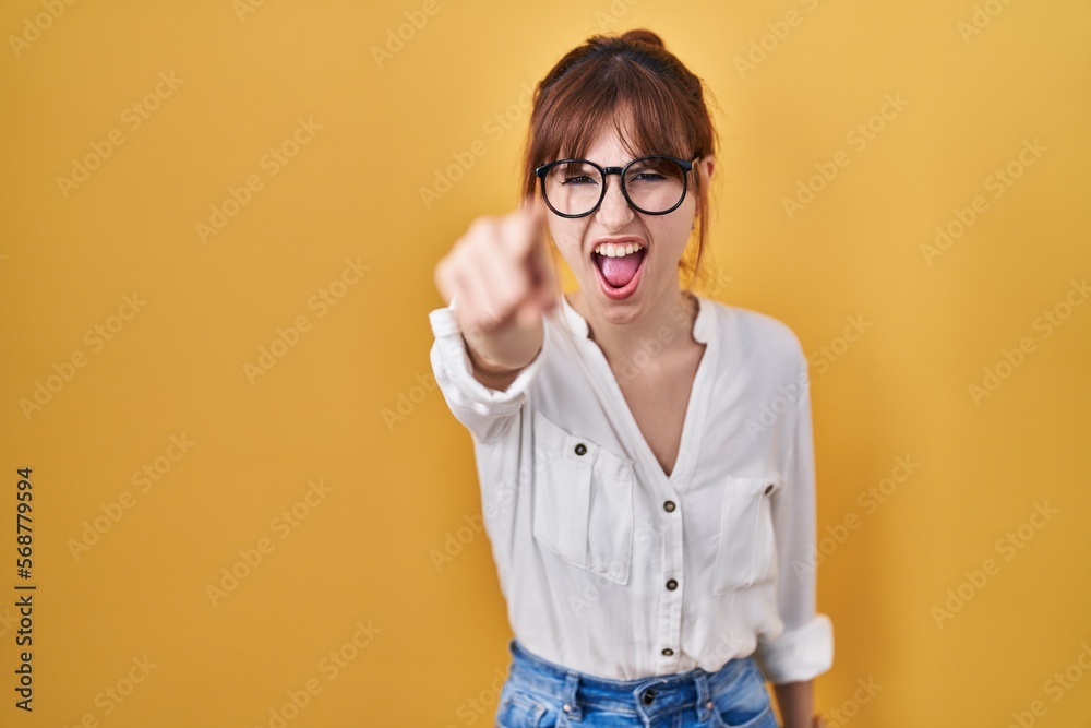 Young beautiful woman wearing casual shirt over yellow background pointing displeased and frustrated to the camera, angry and furious with you