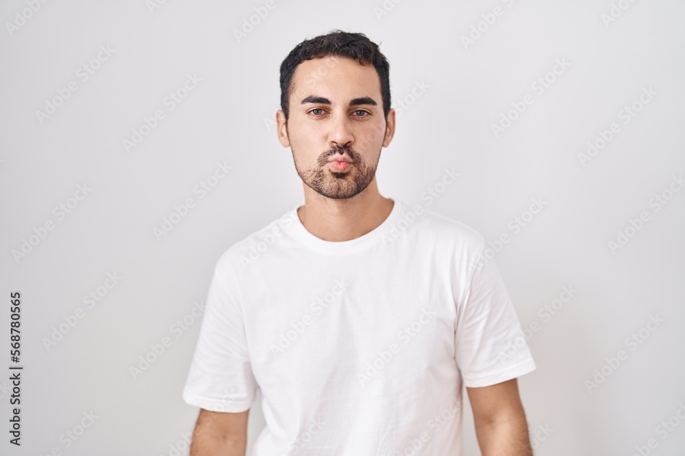 Handsome hispanic man standing over white background looking at the camera blowing a kiss on air being lovely and sexy. love expression. Handsome hispanic man standing over white background looking at the camera blowing a kiss on air being lovely and sexy. love expression.