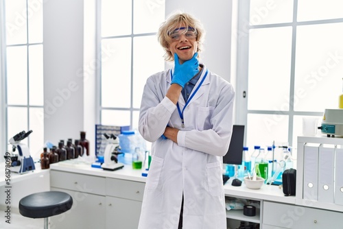Young blond man scientist smiling confident standing at laboratory