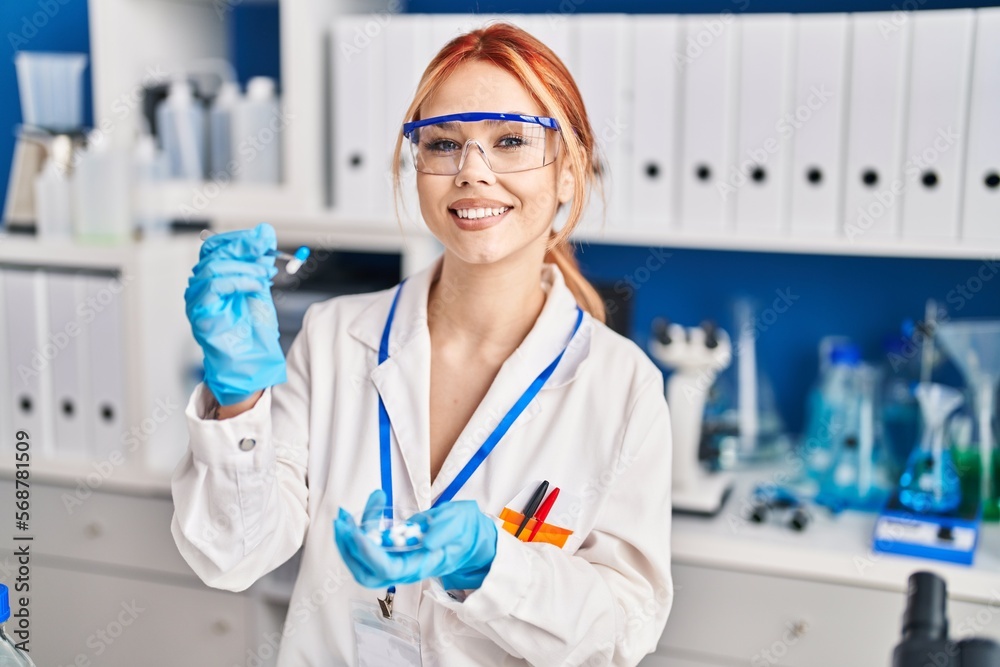 Young caucasian woman scientist smiling confident holding pill at laboratory Young caucasian woman scientist smiling confident holding pill at laboratory