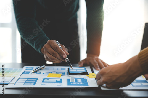 ux developers and ui designers, data researchers brainstorm on tabletop mobile app interface wireframe design with client summary color codes the modern office Creative Digital Development Agency.