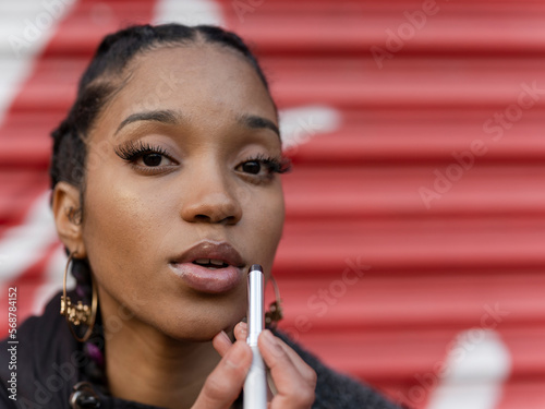 Young woman applying make-up, portrait