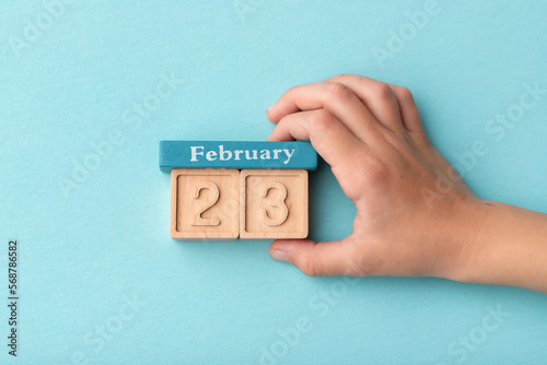 Hand holding calendar february date 23 on a blue background