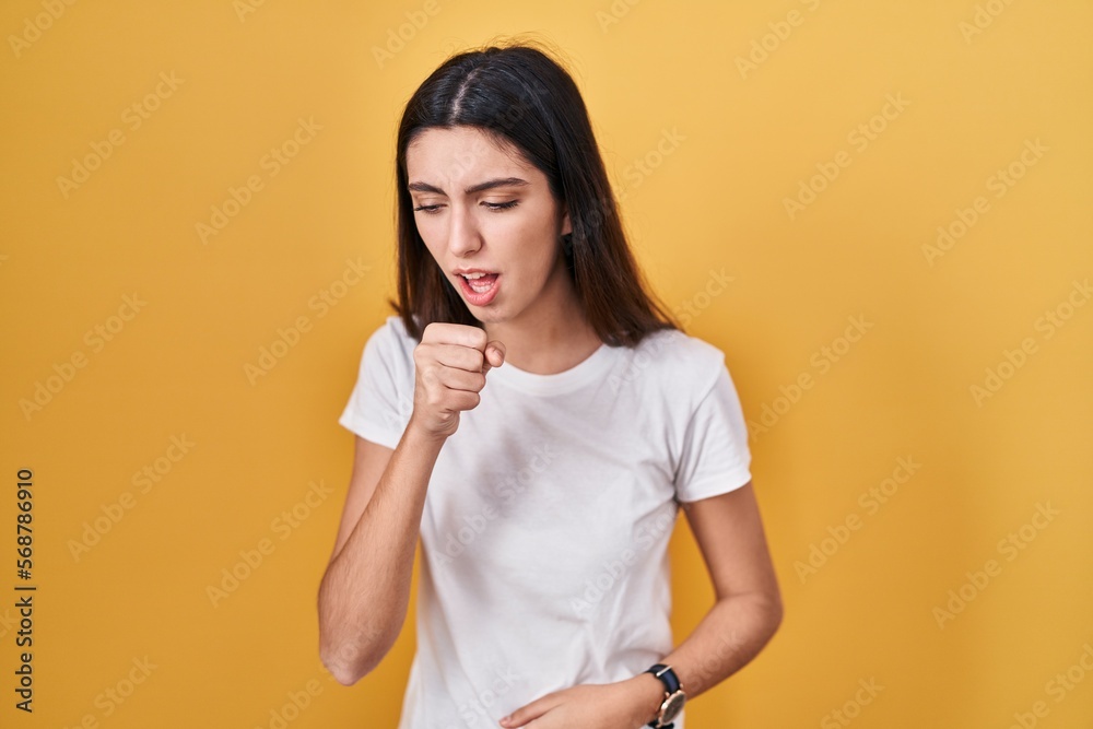 Obraz premium Young beautiful woman standing over yellow background feeling unwell and coughing as symptom for cold or bronchitis. health care concept.