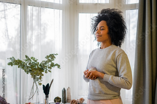 Obraz na plátně Smiling young woman holding crystal at home
