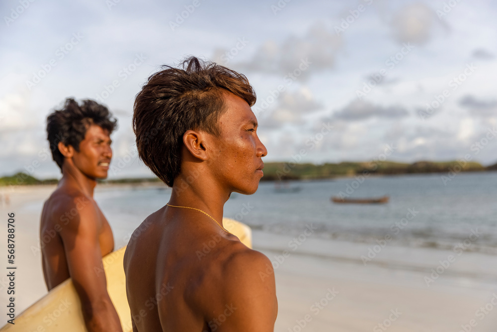 Indonesia, Lombok, Side view of surfers looking at sea from beach Indonesia, Lombok, Side view of surfers looking at sea from beach