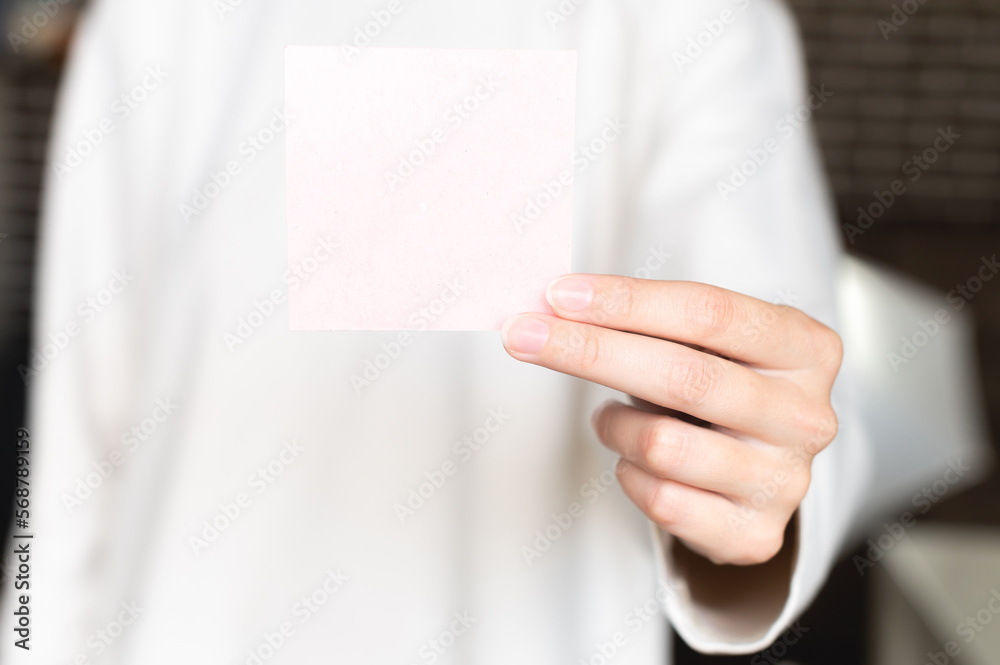 woman is holding a square empty blank sticker in her hands. Background space for text or advertising or reminder woman is holding a square empty blank sticker in her hands. Background space for text or advertising or reminder