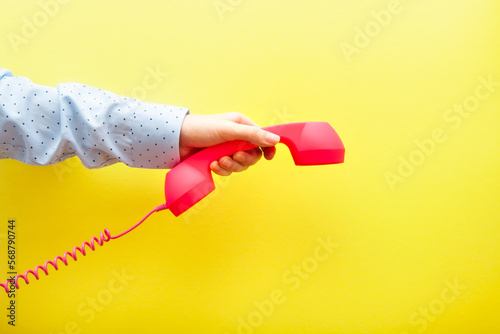 Woman hand hanging up pink phone on yellow background, communication and connection concept