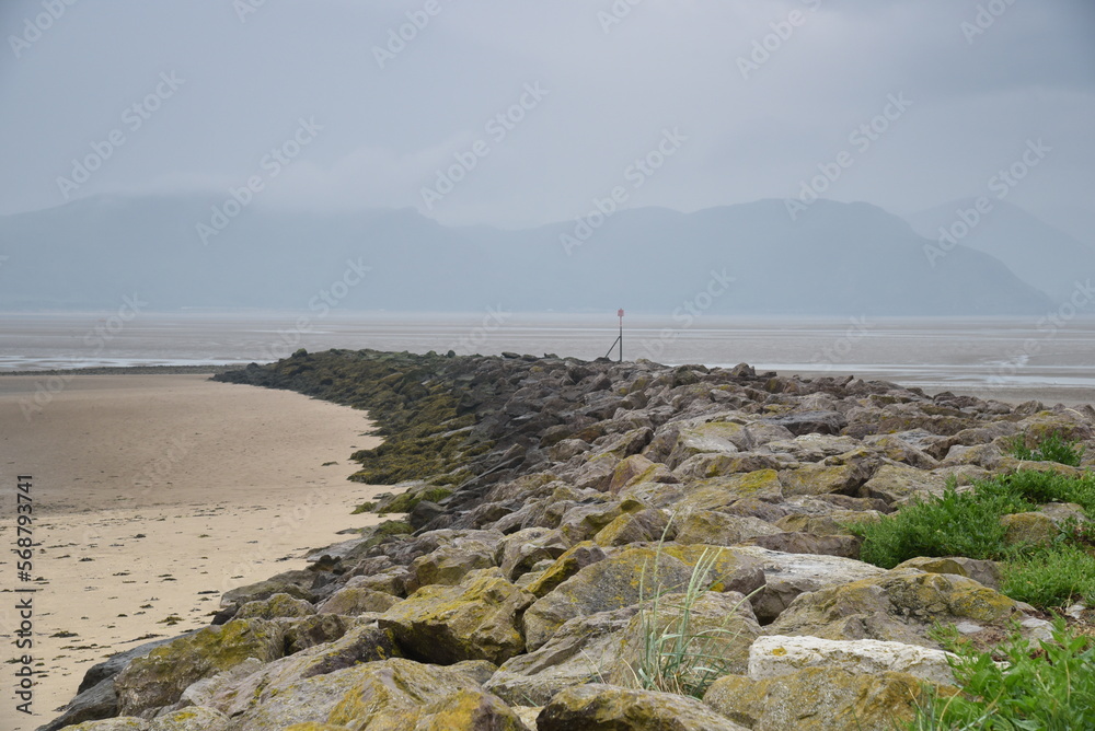 Rocky outcrop on beach with hazy cli