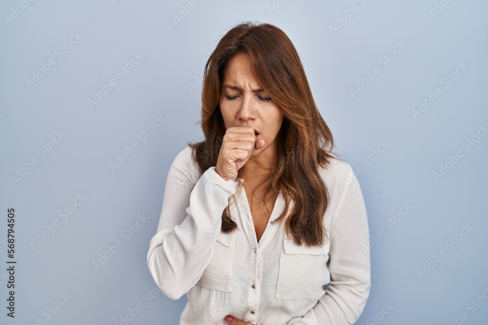 Hispanic woman standing over isolated background feeling unwell and coughing as symptom for cold or bronchitis. health care concept. Hispanic woman standing over isolated background feeling unwell and coughing as symptom for cold or bronchitis. health care concept.