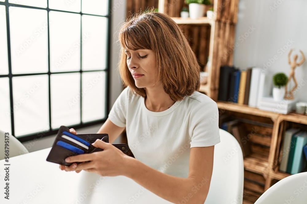 Young caucasian woman looking empty wallet at home Young caucasian woman looking empty wallet at home