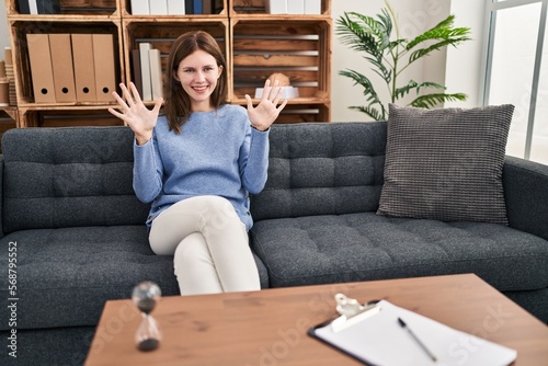 Young brunette woman at consultation office showing and pointing up with fingers number ten while smiling confident and happy. photo