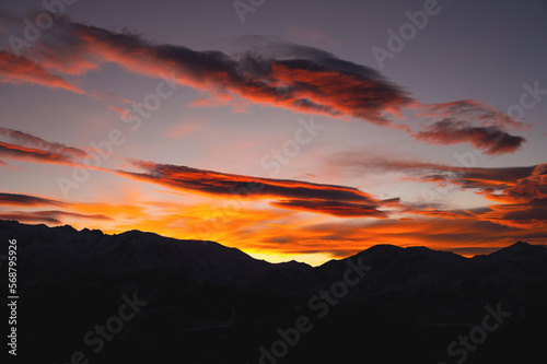 Mountains in the clouds at sunset in summer. Aerial view of the mountain peaks in the fog. Beautiful landscape with high cliffs. Sunset cloud landscape for background
