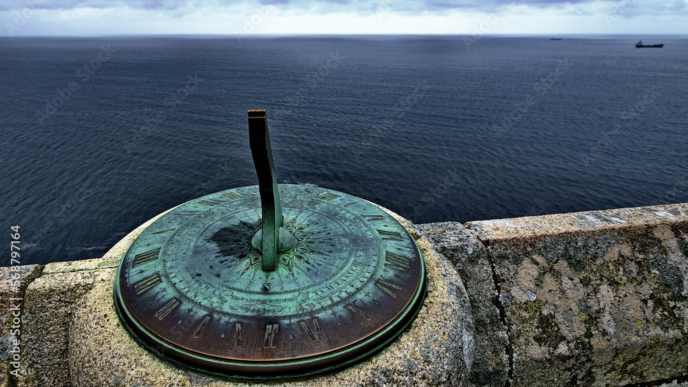 Aged sundial looking out across dark sea 