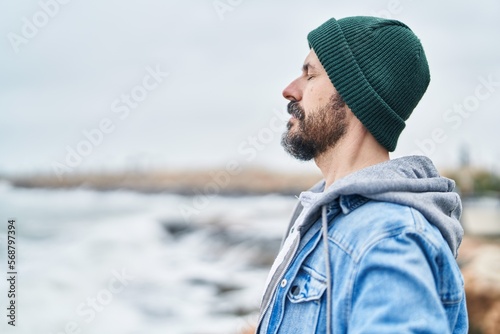Young bald man breathing with closed eyes at seaside