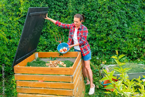 Food waste in a compost bin. A woman in a plaid shirt throws kitchen waste into a DIY compost bin. Aging of compost for its introduction into the soil to improve its structure and fertility.
