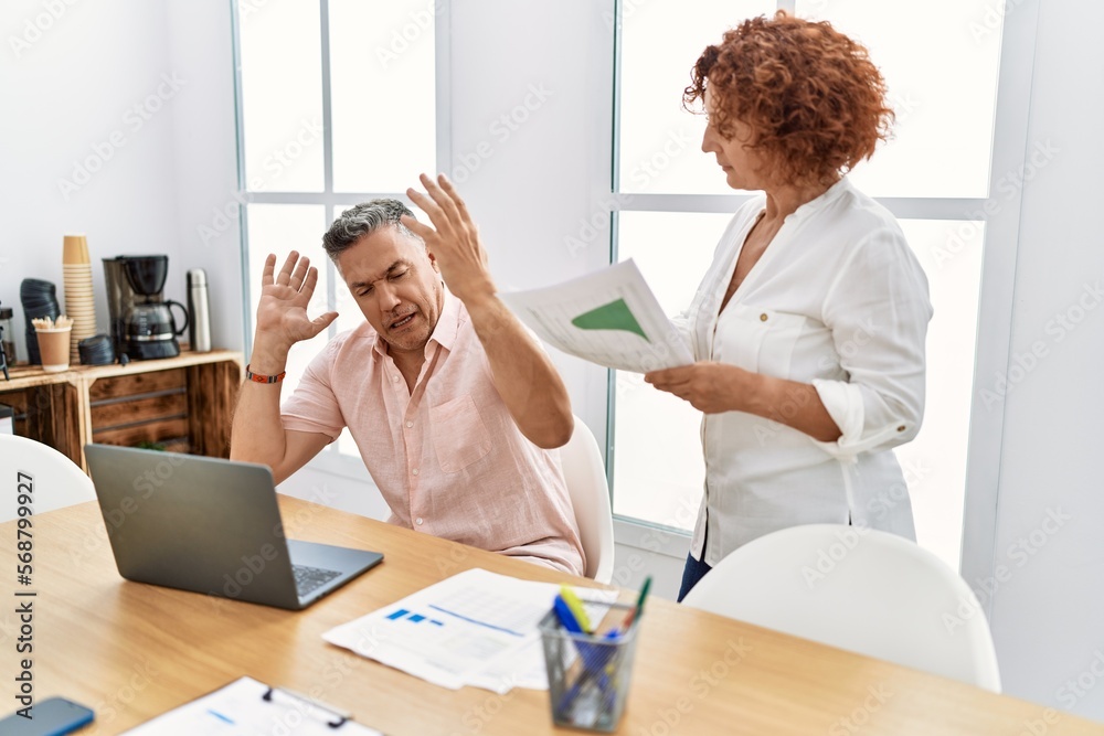 Middle age man and woman business workers arguing at office Middle age man and woman business workers arguing at office